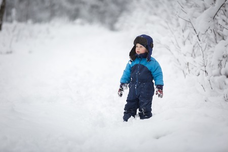 Boy playing in big snow in winter. Happy caucasian child playing in snow.の写真素材