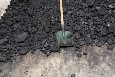 Black coal lying and shovel on a pile in house basement. Fuel material.の写真素材
