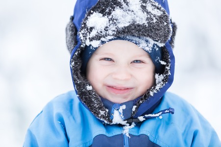 Boy playing in big snow in winter. Happy caucasian child playing in snow.