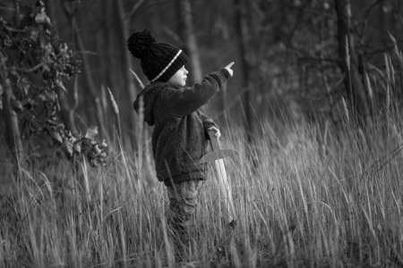 Young boy playing outdoor with wooden sword. Autumnal landscape and young boy.の写真素材