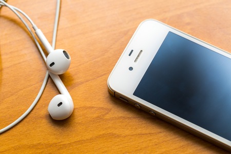 Close up of white headphones lying on wooden table. Small white earphones.の写真素材