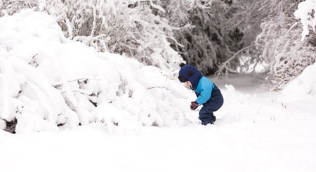 Boy playing in big snow in winter. Happy caucasian child playing in snow.の写真素材