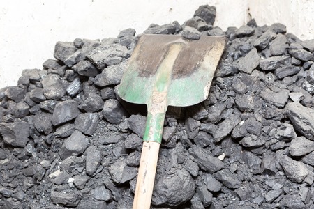 Black coal lying and shovel on a pile in house basement. Fuel material.の写真素材