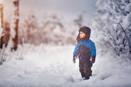 Boy playing in big snow in winter. Happy caucasian child playing in snow.の写真素材