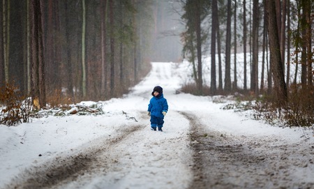 Happy little boy playing outdoor in winter snow. Snowy weather and caucasian child.