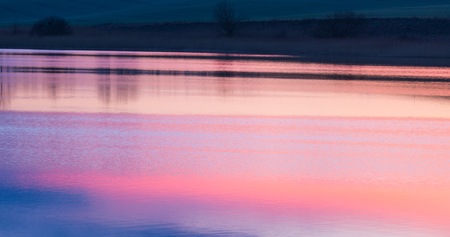 Sky reflecting in lake surface. Sunset over lake. Colorful reflections in water.の写真素材