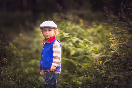 Little boy playing in nature. Caucasian boy and green landscape.の写真素材