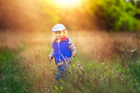 Little boy playing in nature. Caucasian boy and green landscape.の写真素材