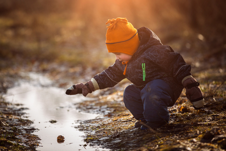 Little boy playing in puddle at springtime. Happy childhoodの写真素材