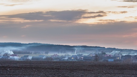 Sunset colorful sky over polish village in spring - spectacular landscape. High smog pollution from the chimneys of housesの写真素材