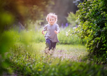 Happy little boy playing outdoor in summer forest. Caucasian blonde boy.の写真素材