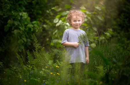 Happy little boy playing outdoor in summer forest. Caucasian blonde boy.の写真素材