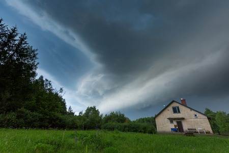 Scarry dark storm clouds over forest and house. Very dangerous weather.の写真素材