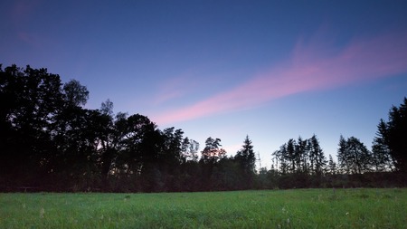 After sunset sky over meadow and forest. Romantic landscape.の写真素材