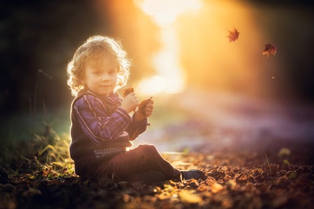 Young blonde boy with long curly hair playing in outdoor.の写真素材