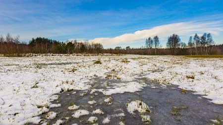 Winter meadows with snow and frozen puddle. Beautiful polish landscape.の写真素材