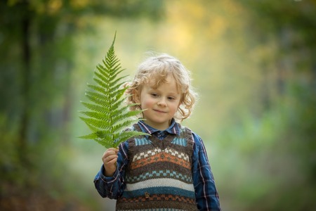 Young blonde boy with long curly hair playing in outdoor.の写真素材