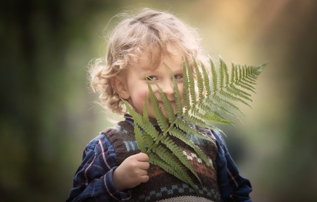 Young blonde boy with long curly hair playing in outdoor.の写真素材