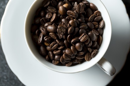 Cup with whole coffee beans. White pot and coffee.の写真素材
