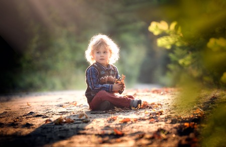 Small boy playing in outdoor in autumnal light. Caucasian kid with curly hair.の写真素材