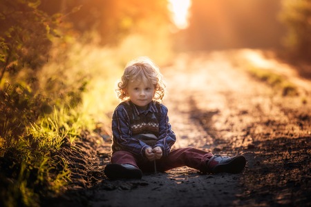 Small boy playing in outdoor in autumnal light. Caucasian kid with curly hair.の写真素材
