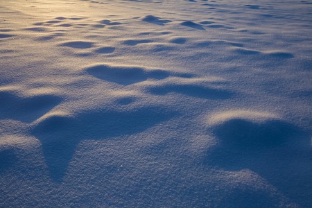 Beautiful snow patterns illuminated with golden sunset light. Winter background.の写真素材
