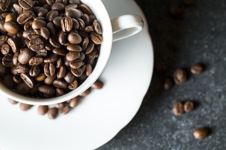 Cup with whole coffee beans. White pot and coffee.の写真素材