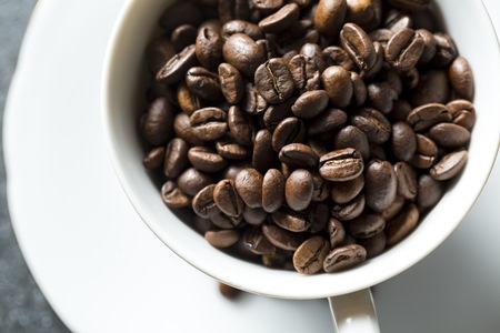 Cup with whole coffee beans. White pot and coffee.の写真素材