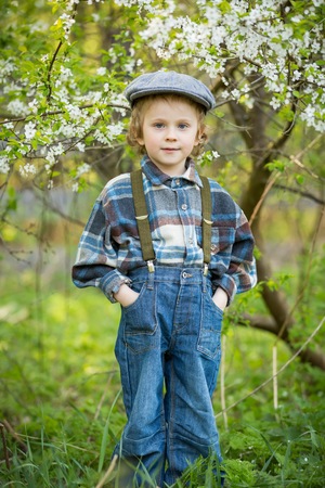 Young blonde boy posing in blooming orchard in springtime.の写真素材