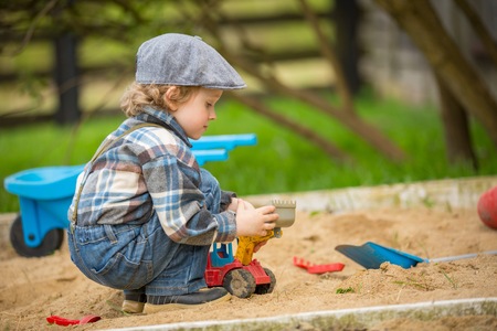 Small caucasian boy playing in sandpit. Handsome blonde 4 years boy in his sandbox.の写真素材