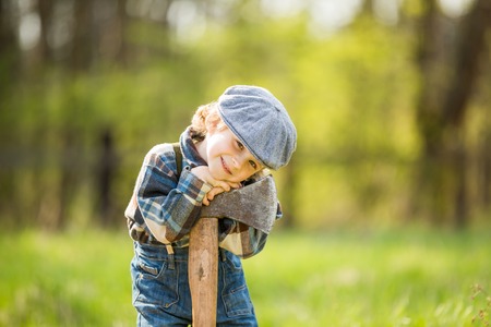 Small caucasian boy in hat posing with big axe. Portrait of small lumberjackの写真素材