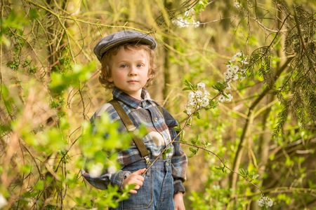 Young blonde boy posing in blooming orchard in springtime.の写真素材