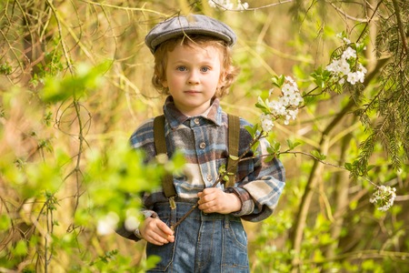 Young blonde boy posing in blooming orchard in springtime.の写真素材