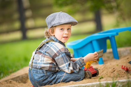 Small caucasian boy playing in sandpit. Handsome blonde 4 years boy in his sandbox.の写真素材