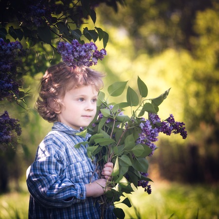 Caucasian boy holding lilac flowers bouquete for his mother. Mother's day flowers bouquete.の写真素材