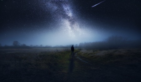 Dreamy surreal landscape with starry night sky and man silhouette.の写真素材