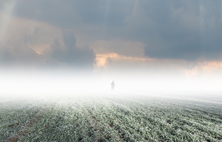 Silhouette of strange man standing in distant fog. Spooky, surreal landscape.の写真素材