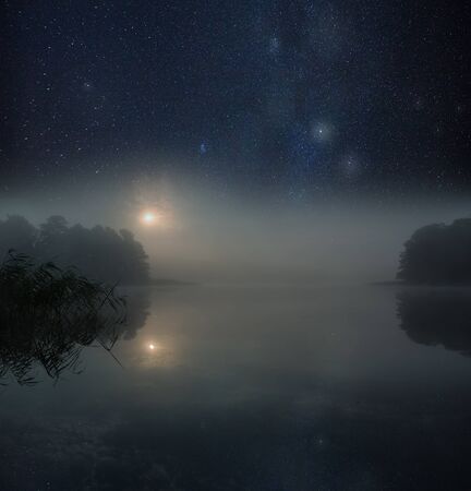 Nigh spooky landscape with foggy lake under satrry sky.の写真素材