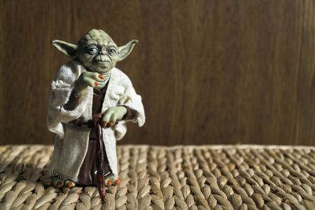 Istanbul, Turkey - October 29, 2016: Master Joda action figure from The Star Wars Movie standing on a wicker furniture with brown wooden background.のeditorial素材