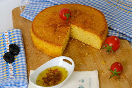 Cornbread cherry tomatoes and olive oil on wooden cutting board and blue white colored plaidの写真素材
