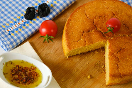 Cornbread cherry tomatoes and olive oil on wooden cutting board and blue white colored plaid from directly aboveの写真素材