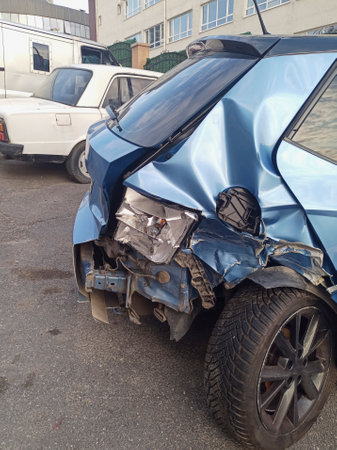 Rear view of a crashed blue hatchback car at street with a broken axle, bumper and taillight.の写真素材