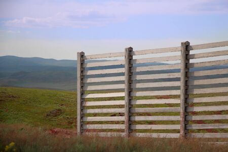 Wooden fence near the road on a background of mountainsのeditorial素材