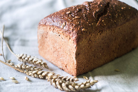 Rustic sourdough artisan bread and wheat on gray kitchen towelの写真素材