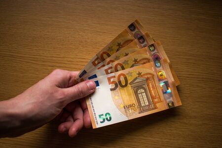 Hands holding paper money, banknotes on wooden background