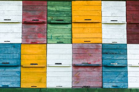 White, red, green, yellow and blue honey beekeeping boxes. Colorful honey beekeeping boxes backgroundの写真素材