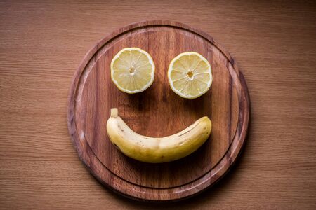 Smile face made of fruits on a wooden round boardの写真素材
