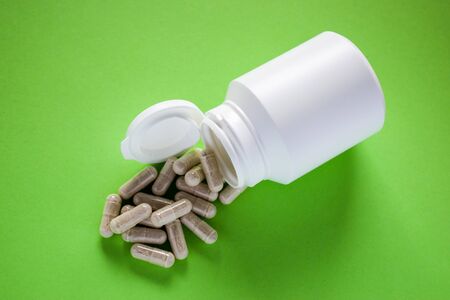 Medical pills, tablets with pill bottle on green background