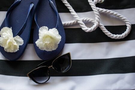 Women flip flops and sunglasses on black and white beach bag with ropes. Summer vacation, travel conceptの写真素材