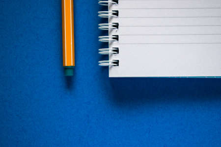 Cut out of yellow pen with some coins on white notepad